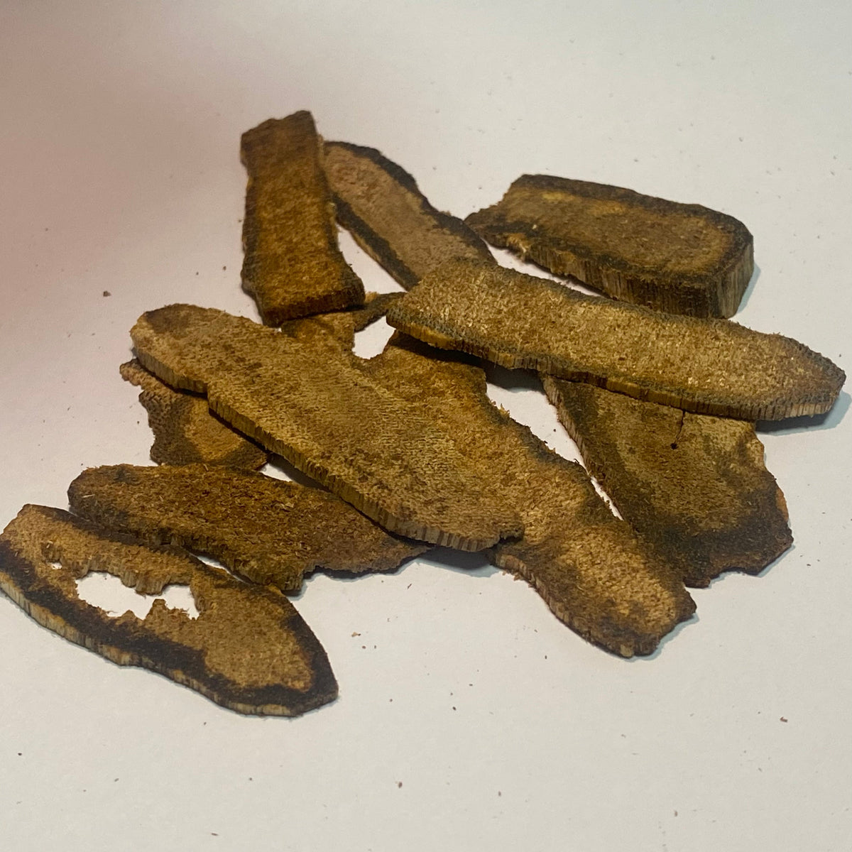 Wild agarwood chips with dark resin veins scattered on a white background