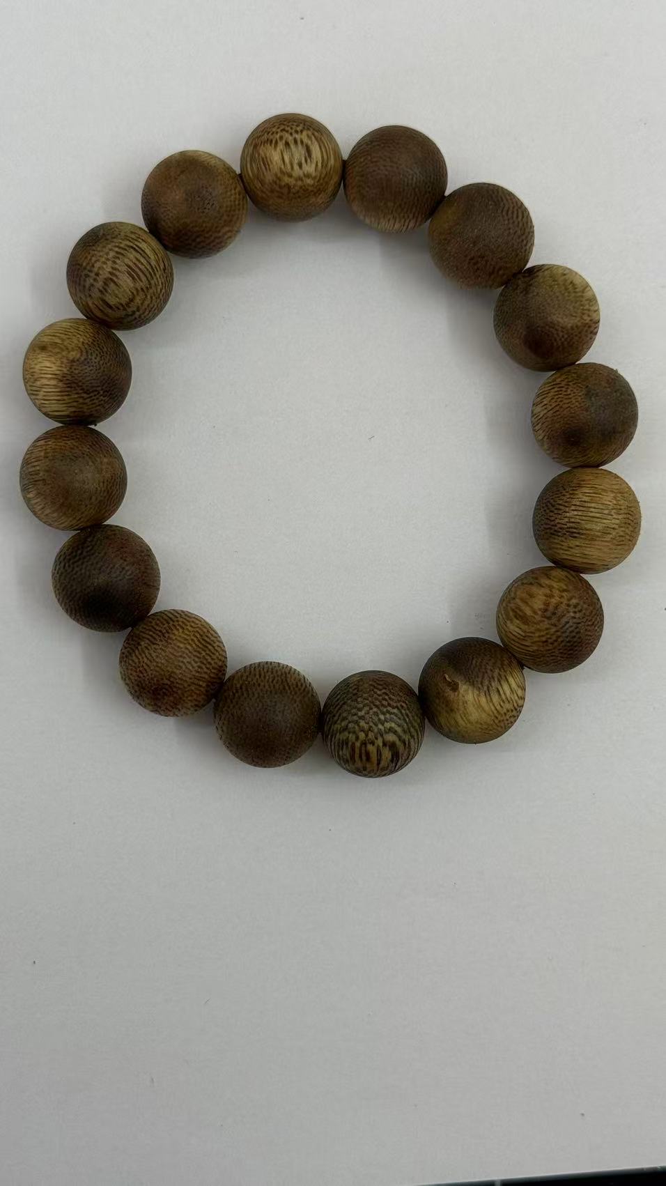 Natural agarwood bead bracelet with dark resin-rich grain on white background